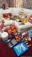 All items on and beside sofa including Hot Wheels case, Mega Bloks bags, books, wagon, dolls, vehicles