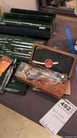Overall view showing green case of instruments, small wooden case with sealed contents and loose compasses