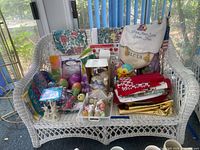 Front view of white wicker loveseat with various items placed on seat
