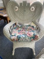 Front view of white wicker rocking chair with floral cushion