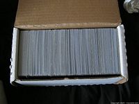 Photo of a large quantity of Pokemon cards neatly stacked in a cardboard box.