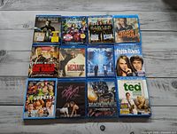 Twelve assorted Blu-ray movie cases arranged in a grid on a wooden surface.