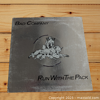 Front cover of Bad Company Run With The Pack vinyl LP showing silver metallic sleeve with dog pack illustration and text.