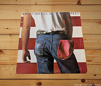 Front of vinyl album cover with iconic American flag background and jeans with red cap.