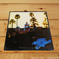 Front cover image of Hotel California album showing the hotel building with palm trees and sunset lighting.