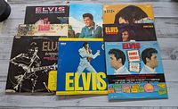 Full view of all 8 Elvis Presley LP records laid out on a wooden surface.