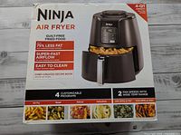 Front of box showing Ninja Air Fryer, highlighting features such as 4-quart capacity, 75% less fat, super-fast airflow, easy to clean, chef-created recipe book, 4 customizable programs, 2 fan speeds, and cooking functions for air fry, roast, reheat, and dehydrate.