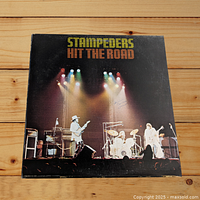 Front cover of the Stampeders LP titled Hit The Road, showing a stage with band performing under colorful lights.