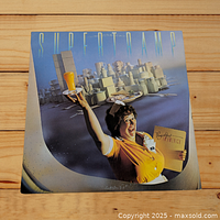 Front cover of Supertramp Breakfast in America LP showing waitress with orange juice and stacked cups in background.