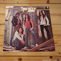 Front cover of Thin Lizzy 'Fighting' vinyl LP album showing band members posing on stone stairs.