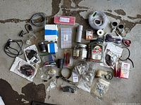 Full layout of all components showing assortment of plastic piping fittings, electrical boxes, wiring, clamps, and packaged components