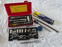 Full layout of socket wrench set and accessories in red case plus loose items on white quilt background