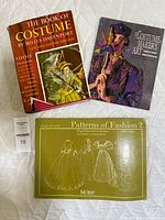 Three costume and fashion reference books laid out on a white surface, titles visible: The Book of Costume, The Costumemaker's Art, Patterns of Fashion 2.