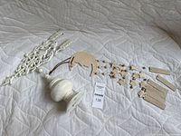 Wind chime components arranged on a quilted white surface showing crescent moon shape and star-shaped dangling pieces connected by strings with beige/off-white finish.