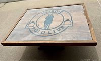Top view of the weathered wood coffee table with the Detroit Polo Club logo under glass.