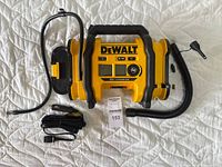 Top view of DeWalt DCC020I air inflator with air hose, power cable, and nozzle adaptors laid out. Inflator has digital display and yellow-black color scheme.