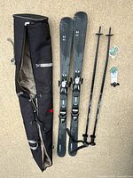 Photo showing full ski set with bag, skis, poles, and spare pole baskets spread on ground