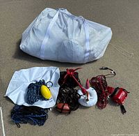 Uninflated inflatable unicorn and accessories lot including ropes, anchor, bouys/fenders, mesh bag, and an electric air pump.