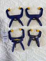 Four blue plastic IRWIN Quick-Grip hand spring clamps, showing front view on quilted surface.