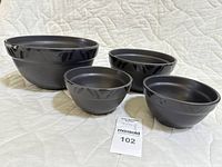 Four black ceramic mixing bowls arranged from largest to smallest showing their size difference, finish, and shape.