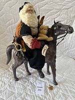 Front side view of Santa Claus figure on horse showing detailed clothing, teddy bear, skis, and accessories.