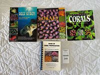 Front covers of four aquarium coral and reef keeping books arranged on a white textured surface.