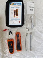 Photo showing the full wire tracker kit including emitter, receiver, cables, earphone, battery, and carrying pouch with instruction sheet.