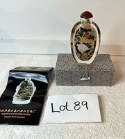 Snuff bottle standing on top of the travel box, accompanied by a folded brochure booklet and lot paper.