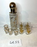 Full lot showing dispenser and two sets of glasses arranged on white surface with Lot 53 card.
