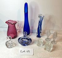 Photo of lot showing purple/cranberry colored pitcher, tall cobalt blue vase, blue and clear twisted glass vase, clear glass swan, square and round Dansk candle holders, and vintage Czech crystal salt and pepper shakers.