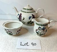 Front angled view of teapot, creamer, and sugar bowl showing botanical patterns and overall condition