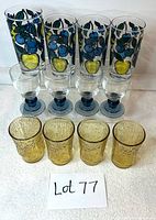 Photo of 12 drinking glasses arranged in three sets: 4 tall Dominion blue and yellow cherry/apple glasses, 4 Luigi Bormioli blue cordial stemmed glasses, and 4 amber textured MCM Anchor Hocking glasses.