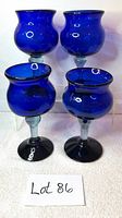 Four cobalt blue margarita glasses with clear stems, showing their shape and color from an angled view.