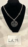 Front view of the sterling silver necklace with the 4-strand chain and round pendant on a black bust display.