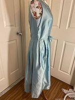 Side view of blue satin vintage dress on mannequin, showing full skirt and fitted bodice