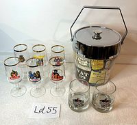 View of all glassware including 6 stemmed beer glasses with assorted logos, 2 Captain Cola whiskey glasses, and the chrome whisky label ice bucket.