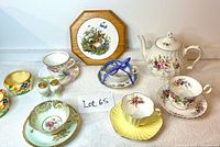 Photo of entire lot showing all porcelain items arranged on a white surface including teapot, cups, saucers, sugar and creamer, salt and pepper shakers, and bunny trivet against a plain background