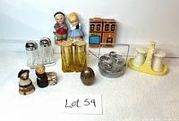 Photo overview of all 8 salt and pepper shaker sets and related pottery or collectible items on white surface