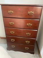 Front view of the 5 drawer wooden dresser with brass handles showing overall condition and style.