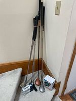 Photo showing the golf clubs including irons, putter, and wood-type drivers along with two boxes of TaylorMade Distance golf balls and a boxed MILESEEY PF210 laser rangefinder