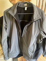 Front view of gray Lululemon men's jacket on hanger, zippered, stand collar
