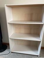 Front view of white shelving unit showing three shelves and rectangular shape.