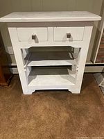 Front view of white wooden console table with two drawers and two shelves.