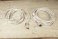 Two coiled white cables laid side by side on a bench with connectors visible