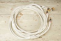 Overhead view of two coiled white speaker cables with banana plug ends