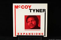 Front cover of McCoy Tyner's Expansions LP showing bold red and black text with red photo of McCoy Tyner.