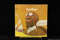 Front cover of Solo Monk album featuring illustrated portrait of Thelonious Monk in pilot gear on yellow background.