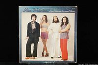 Front cover of Max Webster 'High Class in Borrowed Shoes' vinyl LP. Shows four band members in color photo with blue border and album title.