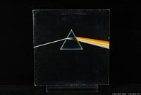 Front cover of Pink Floyd's The Dark Side of the Moon album showing iconic prism with light and rainbow spectrum on black background.