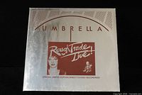 Front cover of the limited edition Rough Trade Live! vinyl LP showing silver background with burgundy text and artwork.